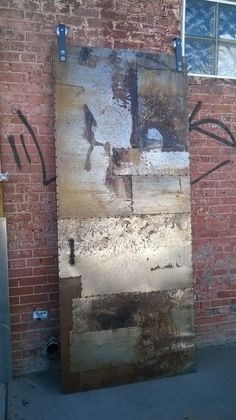 an old door with graffiti on it in front of a brick building