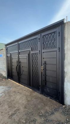 a large black gate with intricate carvings on it's sides and side doors, in front of a building