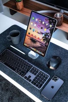 an ipad, keyboard and mouse on a desk next to a computer monitor with the screen open