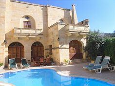 an outdoor swimming pool with chaise lounges in front of a large stone building