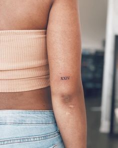 a woman's arm with a small roman numeral tattoo on her left arm