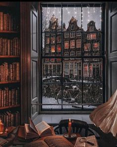 an open book on a table in front of a window filled with books and candles