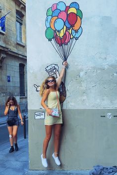 a woman leaning against a wall with balloons painted on it