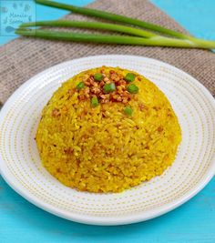 a white plate topped with yellow rice and green onions