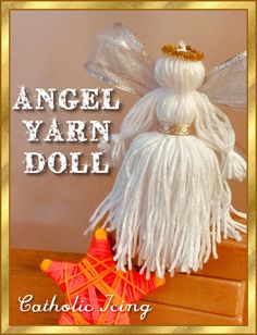 an angel yarn doll sitting on top of a wooden table next to a red star