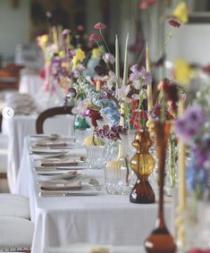 a long table with many different colored flowers in vases