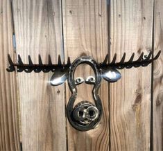 a metal hook on the side of a wooden fence with nails sticking out of it