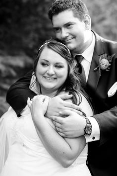 a bride and groom hugging each other in black and white