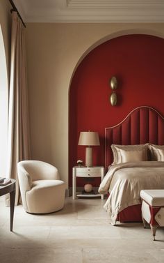 a bedroom with a red wall and white furniture in the corner, along with a large bed