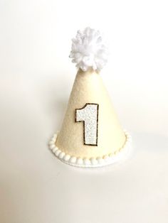 "These MINI party hats are the perfect accessory for your little one's big day or photo session. All hats are made to order. Each hat along with the bows and embellishments are carefully handcrafted so each hat is unique and will vary slightly because of this.  PLEASE LEAVE YOUR EVENT DATE AT CHECKOUT. PARTY HAT FEATURES: -Mini Party Hat (approximately 3\"x5\")  -Ivory/linen felt-covered hat designed with a custom template -White glitter number with white border or gold glitter border (of your c Pastel Cake Smash, Mini Birthday Cake, Mini Party Hats, Mini Pinscher, Glitter Number, Daisy Party, Twins 1st Birthdays, Mini Cakes Birthday, Hat Headband