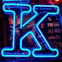 a neon sign in front of a store window with the letter k on it's side