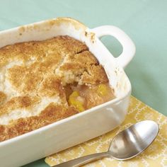 a casserole dish on a yellow and white napkin with a spoon next to it