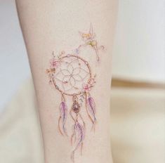 a woman's leg with a dream catcher tattoo on her left thigh and hummings flying around it