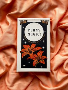 a card with the words plant magic on it sitting on an orange cloth covered bed