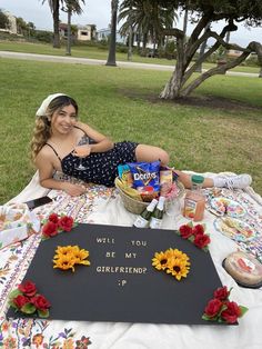 a woman sitting on top of a blanket next to a sign