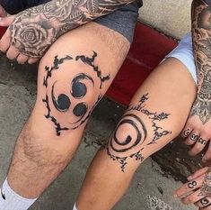 two people with tattoos on their legs sitting next to each other and holding hands together