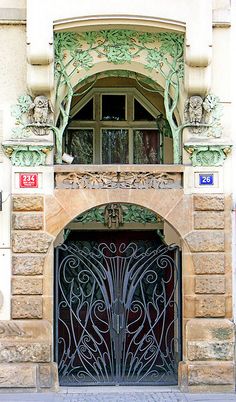 the entrance to an old building with wrought iron doors and decorative carvings on it's sides