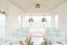 an outdoor wedding venue with blue and white chairs on the deck, overlooking the water