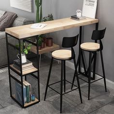 two stools and a table with books on it in a living room next to a couch