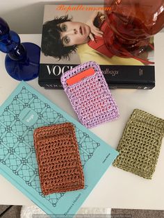 three crocheted cell phones sitting on top of a table next to a book