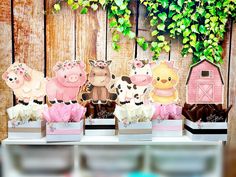 there are many farm animals on display in this table toppers set up with pink and white flowers