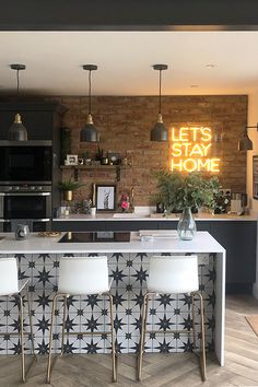 a kitchen with an island and bar stools in front of the counter, next to a brick wall