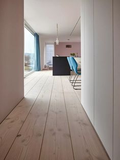 an empty room with wooden floors and blue chairs on the side wall in front of a sliding glass door