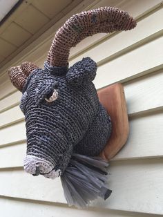 an animal made out of knitted material hanging on the side of a house