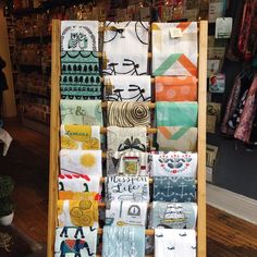 a display in a store filled with lots of different types of cloths on wooden racks