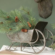 a metal sleigh with pine cones and branches in it