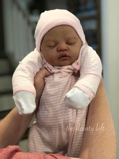 a woman holding a baby wearing a pink hat and striped dress with white gloves on