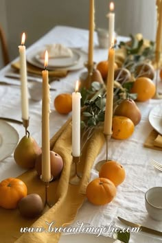 the table is set with oranges, pears and other fruit on it as well as candles