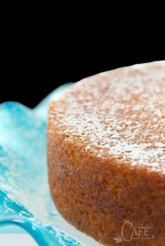 a cake with powdered sugar on it sitting on a blue and white plate in front of a black background