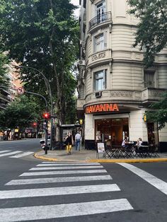 people are walking on the sidewalk in front of a building that has an awning