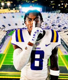 a man with dreadlocks is holding his hand up to his face in front of an empty stadium