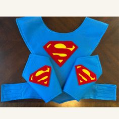 a blue shirt with red and yellow supermans on it, sitting on top of a wooden table