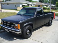 a black pick up truck parked in front of a house