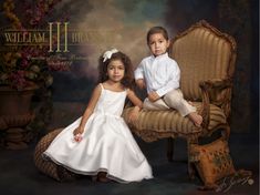 two children sitting on a chair in front of a backdrop