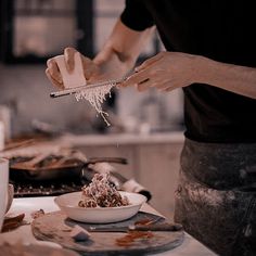 a person in the kitchen sprinkles food into a bowl