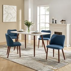 a dining room table with blue chairs and a rug on the floor in front of it