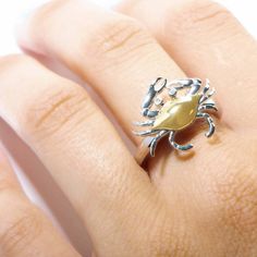 This 925 sterling silver ring features our original crab motif with 14K solid yellow gold and diamonds. Blue crabs live along the Atlantic Coast. Its scientific name—Callinectes sapidus—translated from Latin means 'beautiful savory swimmer.' The crab symbol encourages you to let your guard down for the right people, and not allow yourself to be washed over by emotions. Details: Brand: Alamea Materials: 14K Gold, 925 Sterling Silver, Rhodium-plated Polished Finish & Sand Blasted Gemstone: Diamond Blue Crabs, The Crab, Blue Crab, The Atlantic, Solid Yellow, 925 Sterling Silver Ring, Crab, Rhodium Plated, Sterling Silver Ring