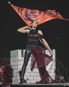 a woman is holding an orange and purple flag in her hand while standing on stage