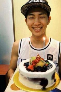 a young man holding a birthday cake with a lit candle