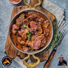 a large pot filled with beef stew on top of a wooden cutting board next to other food