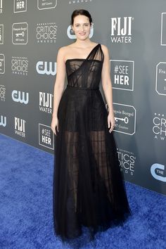 a woman in a black dress standing on a blue carpet