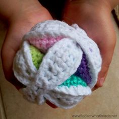 a person holding a small crocheted object in their hands