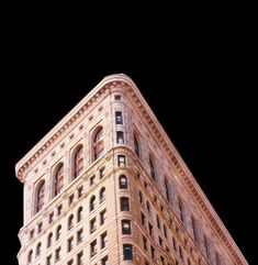 a tall building with lots of windows on it's side and the top half lit up at night