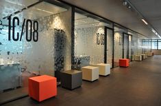 an office with glass walls and orange chairs