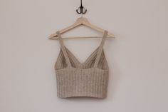 a cropped top hanging on a hanger next to a white wall and a wooden coat rack