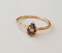 a gold ring with an oval shaped brown diamond in the center, on a white surface